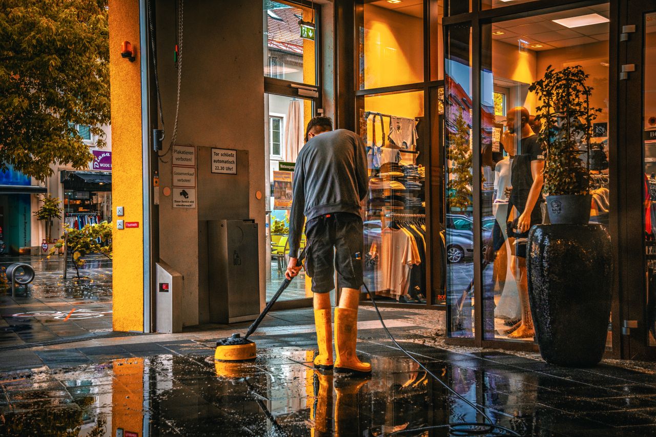 Mastering the First Impression: Your intriguing post title goes here A man cleans the entrance of a store during a rainy day, reflecting urban life.